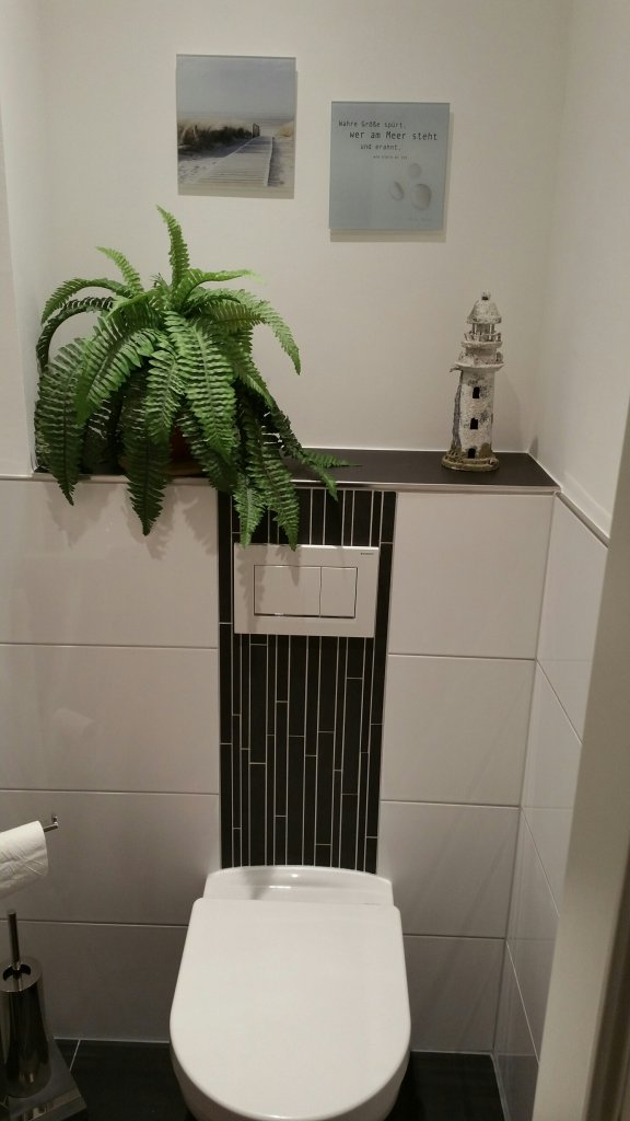 Modernes WC mit Unterputzspülkasten, der voll gefliest als Ablagefläche dient